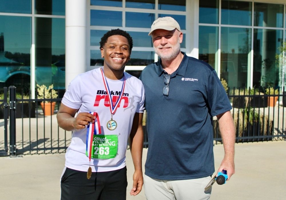 Participant posing holding medal — 2026 Strides for Autism