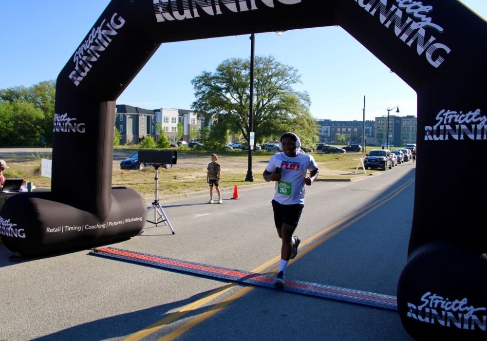 Runner headphones crossing finish line — 2026 Strides for Autism