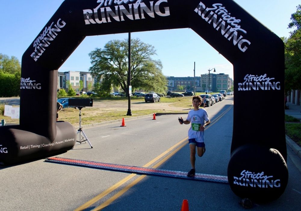Young runner crossing finish line — 2026 Strides for Autism